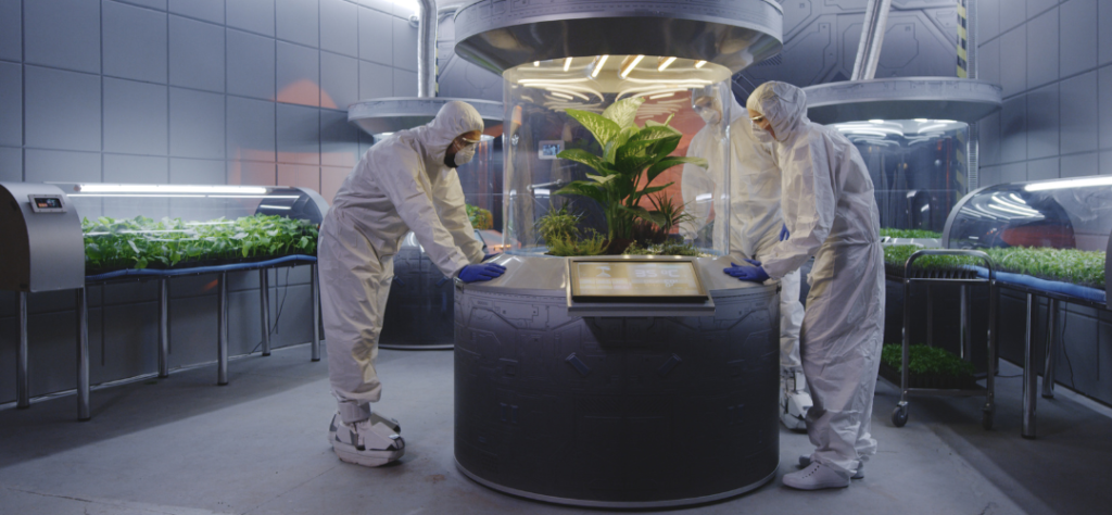 Astrobiologia e sinais potenciais de vida fora da Terra: quando a ciência aprende a procurar o impossível 2 Cientistas em trajes de proteção estudando o crescimento de plantas em um laboratório espacial, representando experimentos de biologia em ambientes extraterrestres.