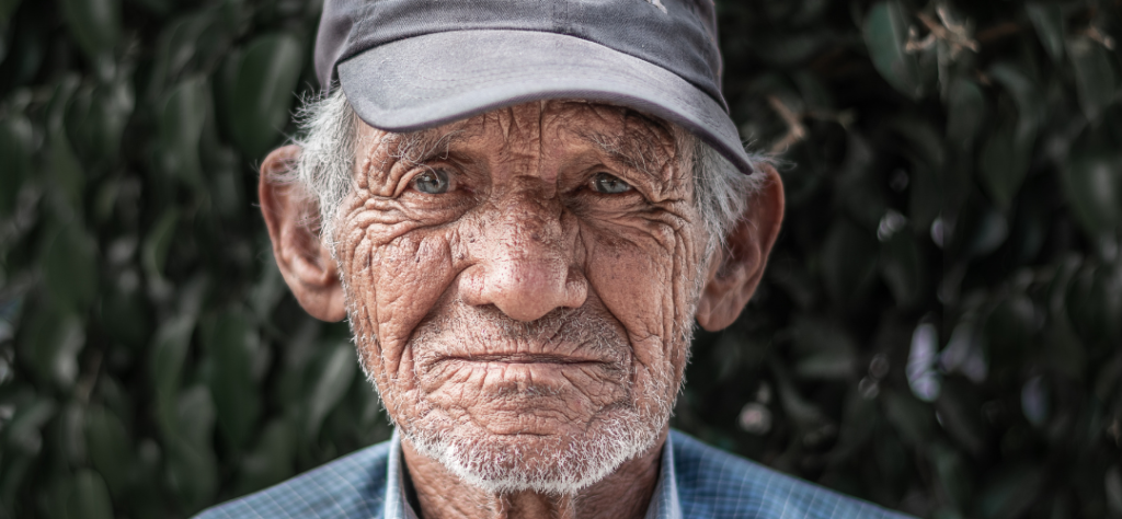 Close do rosto de um homem idoso com rugas profundas, simbolizando o processo natural de envelhecimento e a longevidade.