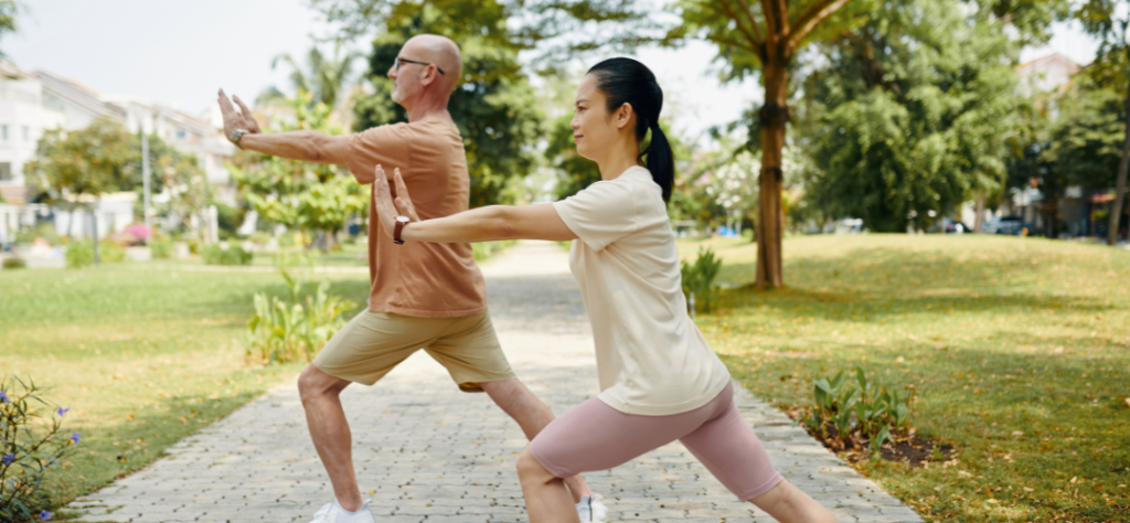 Casal de idosos praticando exercícios físicos em um parque, destacando a importância da atividade física no envelhecimento.
