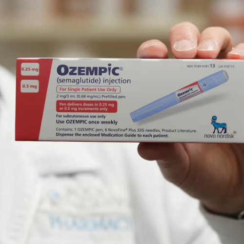 Mão segurando caixa de Ozempic injetável com informações de dosagem e fabricante em destaque.