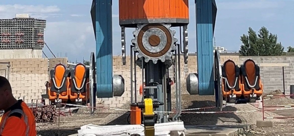 Montagem de atração mecânica com engrenagens gigantes em canteiro de obras do parque temático Naruto.